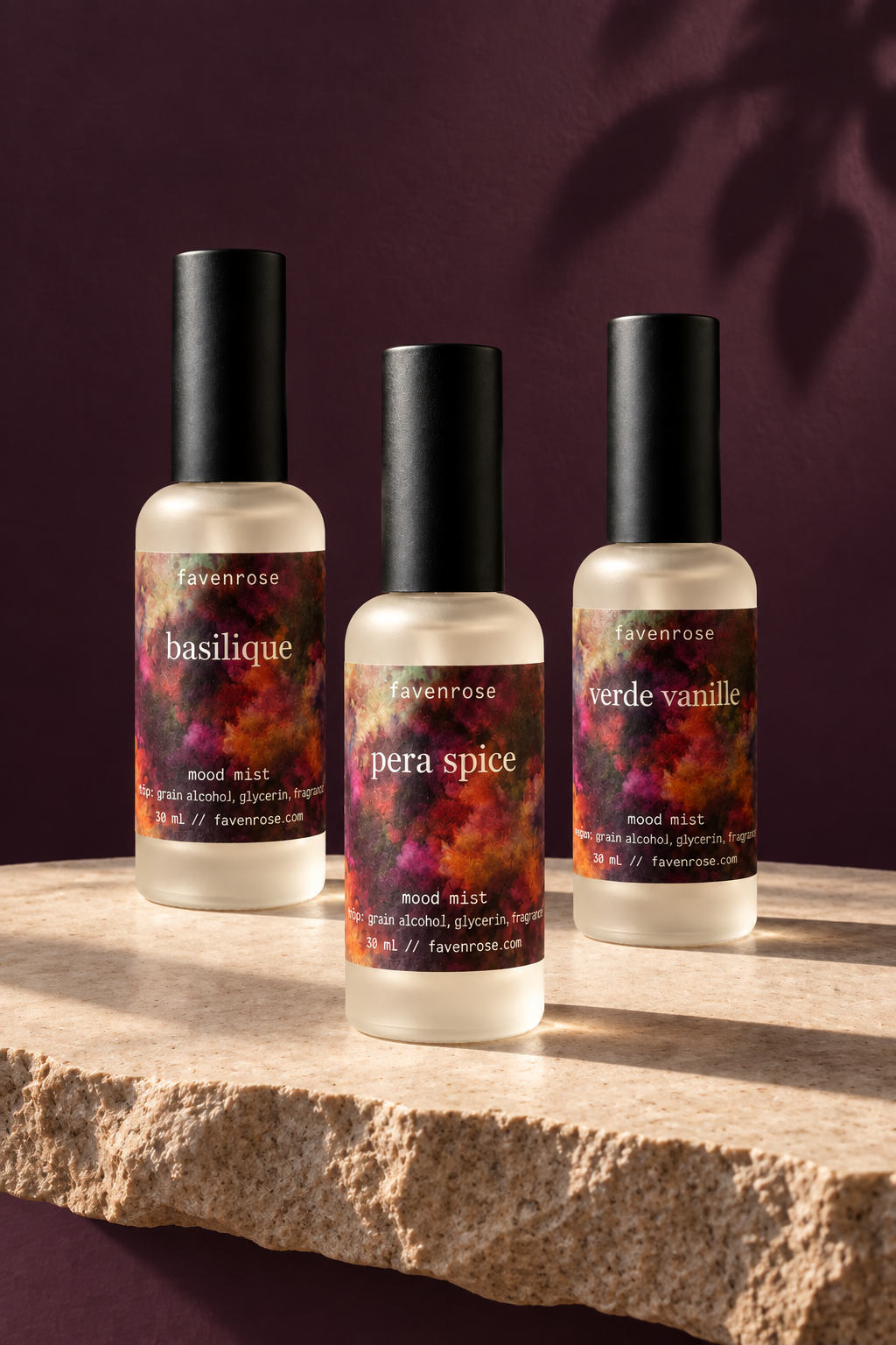 Three Favenrose Mood Mists on raw-edge stone against a dark plum wall