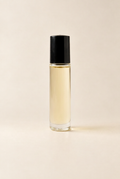 A clear cylindrical glass roller bottle filled with pale yellow liquid, topped with a black cap, centered on a warm beige background.